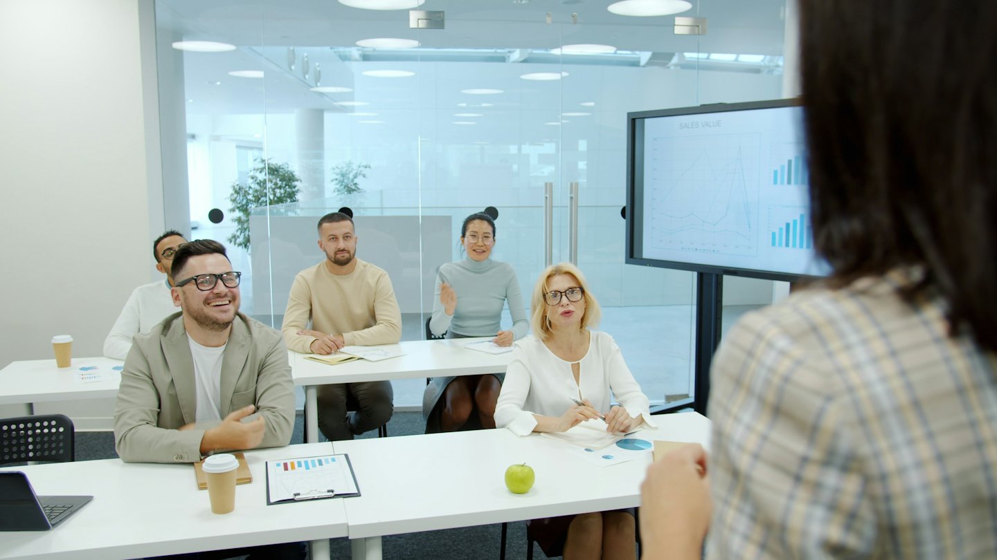 Business professional presenting to diverse attendees in a modern conference room.