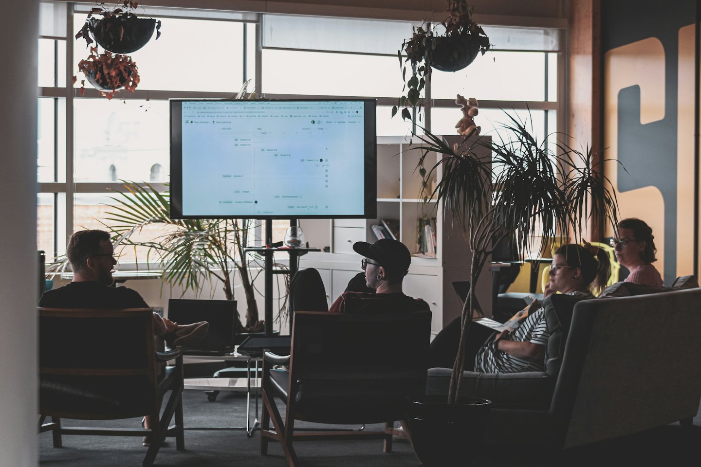 Professionals watch a presentation on a large monitor in a modern office.