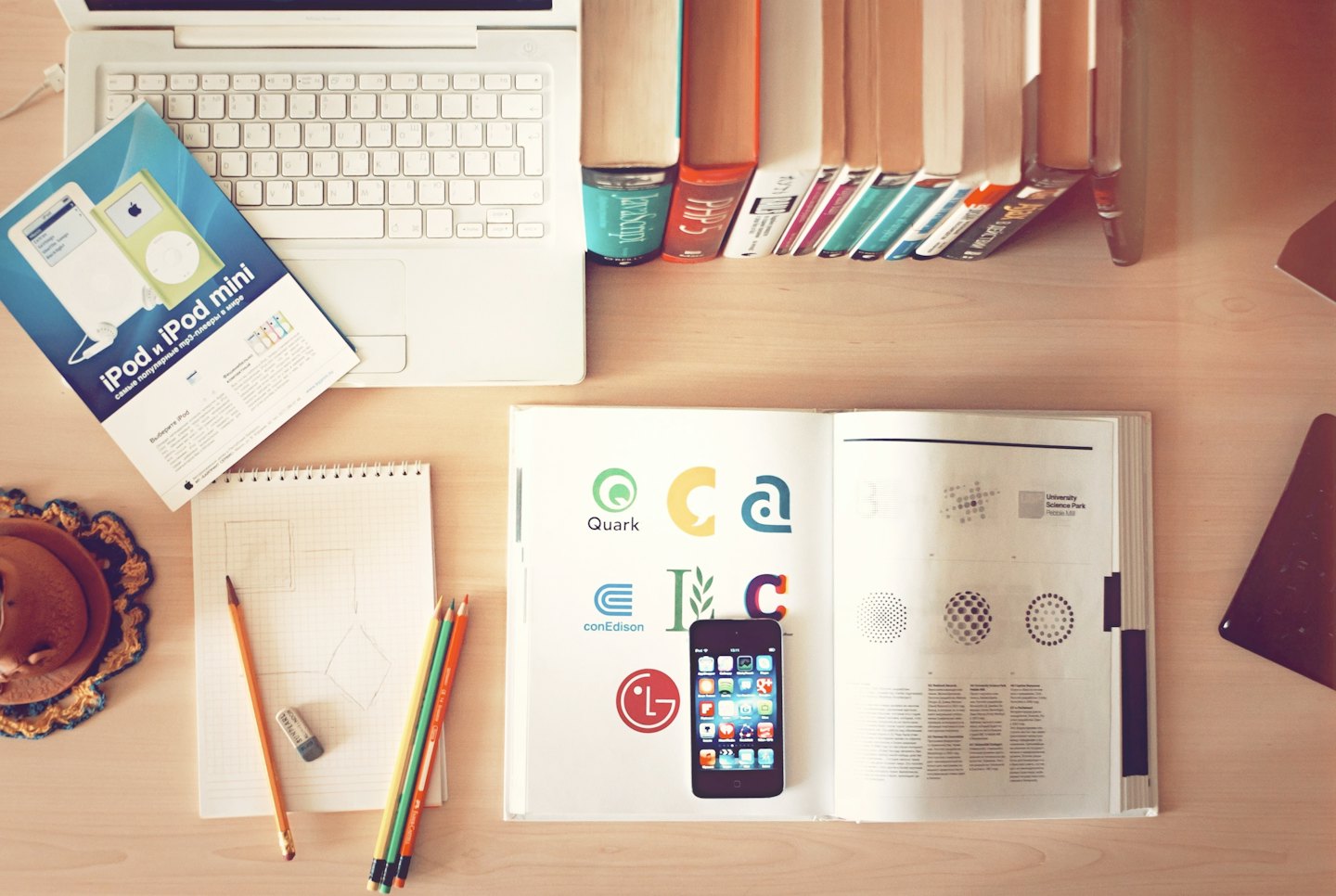 Overhead view of a wooden desk with a laptop and design materials.